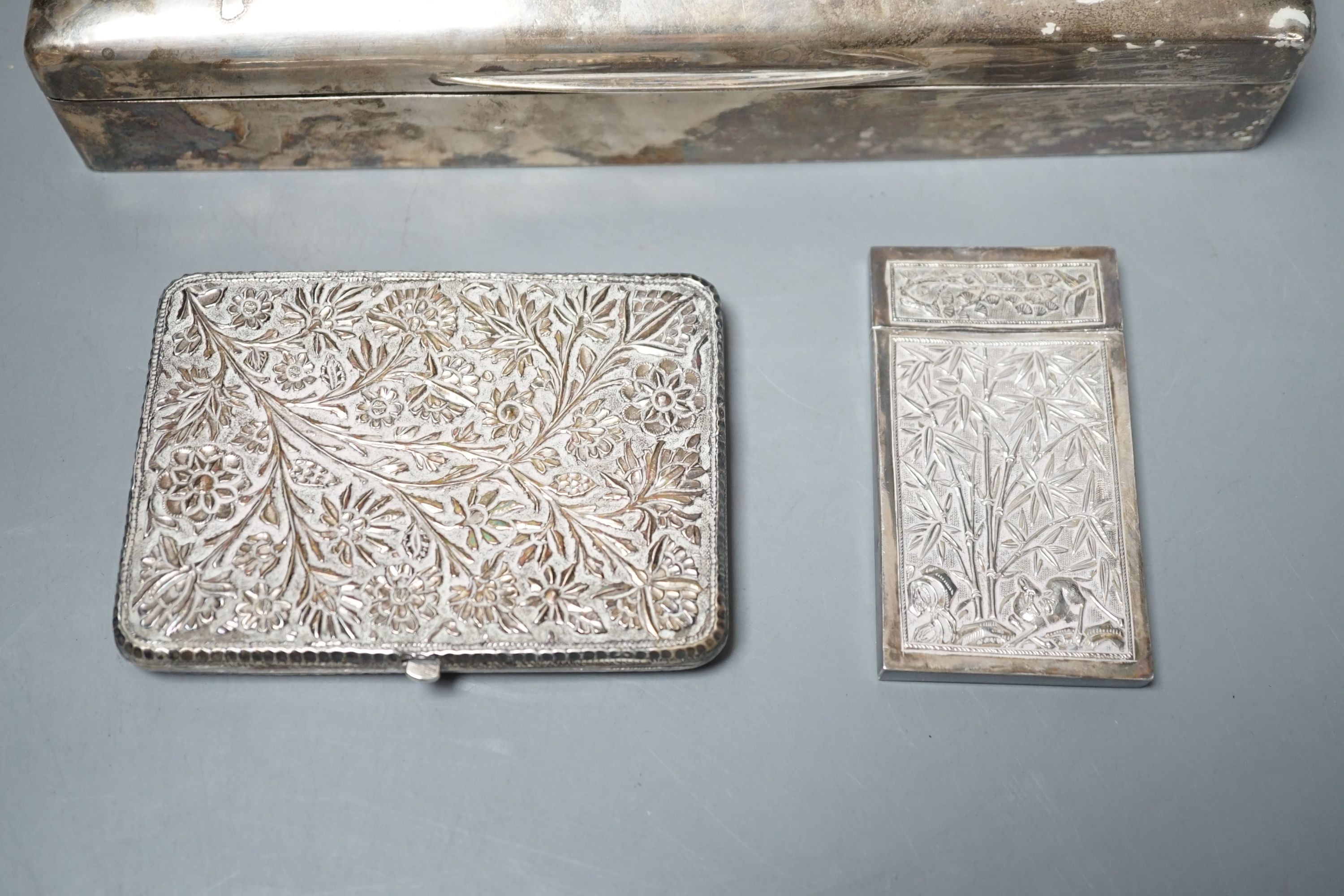 A George V silver mounted cigarette box, London, 1913, 23cm, a Chinese? white metal card case(a.f.) and an Indian? white metal cigarette case.